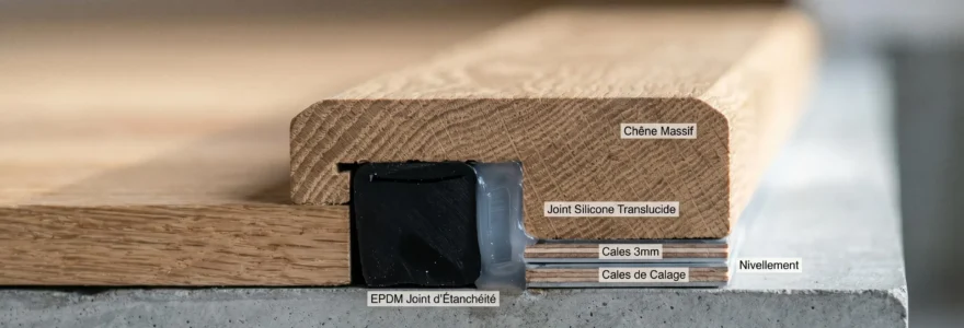 Vue en coupe d'un seuil de porte en chêne révélant les strates d'étanchéité : bande périphérique noire, joint silicone et calage précis, éclairage rasant soulignant les textures bois et matériaux